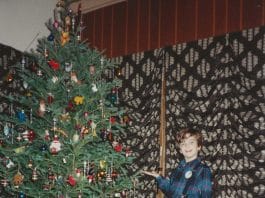 Ben by decorated Christmas tree.
